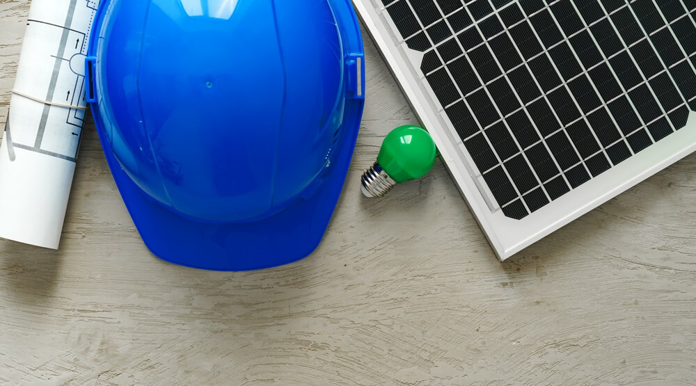 capacete epi, lâmpada verde e um pedaço de placa de energia solar onde simboliza o mercado solar mundial